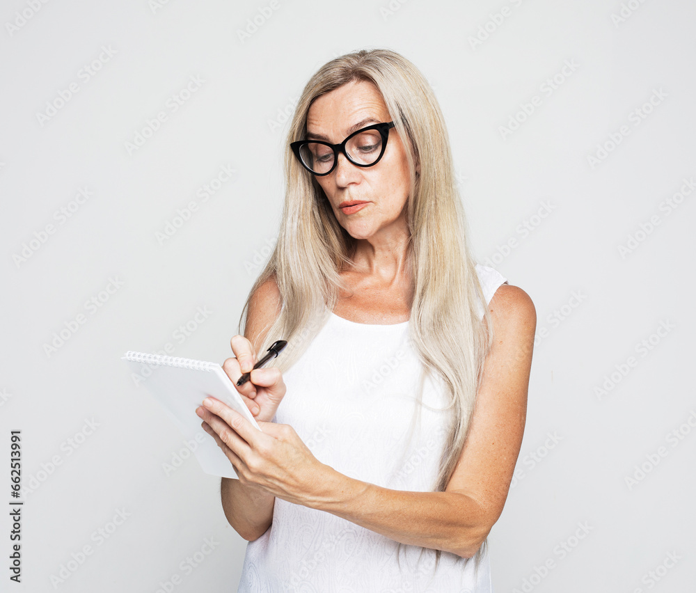 senior female teacher with long white hair writing notes in organizer
