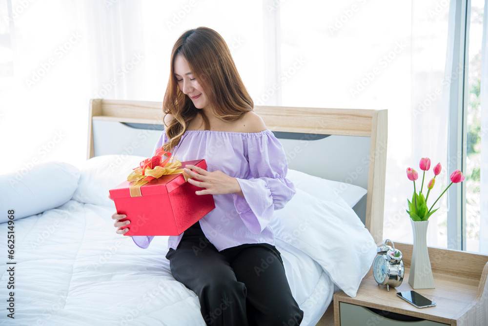 Woman surprise got present gift box on christmas eve. Asian woman holding christmas gift box under xmas tree with smiling face. Woman hands wrap present gift. Merry christmas happy new year concept Woman surprise got present gift box on christmas eve. Asian woman holding christmas gift box under xmas tree with smiling face. Woman hands wrap present gift. Merry christmas happy new year concept