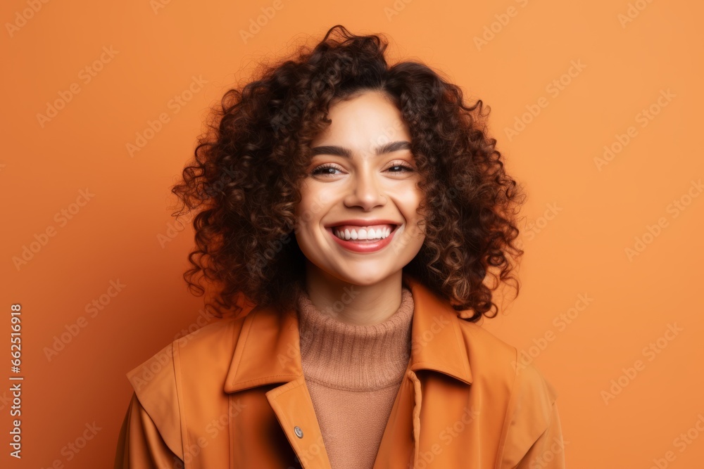 Portrait of smiling young african american woman in orange coat on orange background Portrait of smiling young african american woman in orange coat on orange background