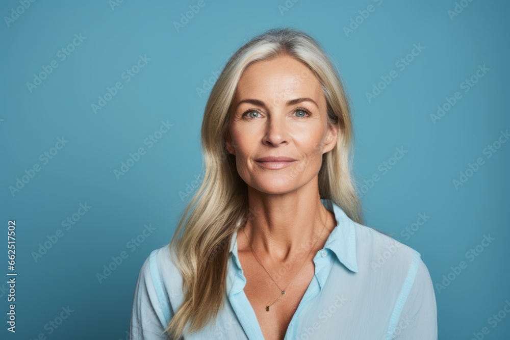 Portrait of happy mature businesswoman looking at camera on blue background Portrait of happy mature businesswoman looking at camera on blue background