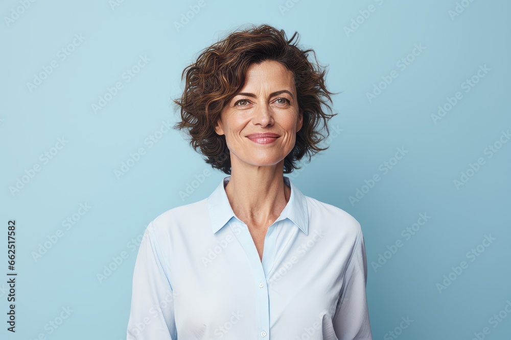 Portrait of smiling middle aged businesswoman with curly hair on blue background Portrait of smiling middle aged businesswoman with curly hair on blue background