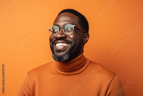 Happy african american man in orange sweater and glasses on orange background