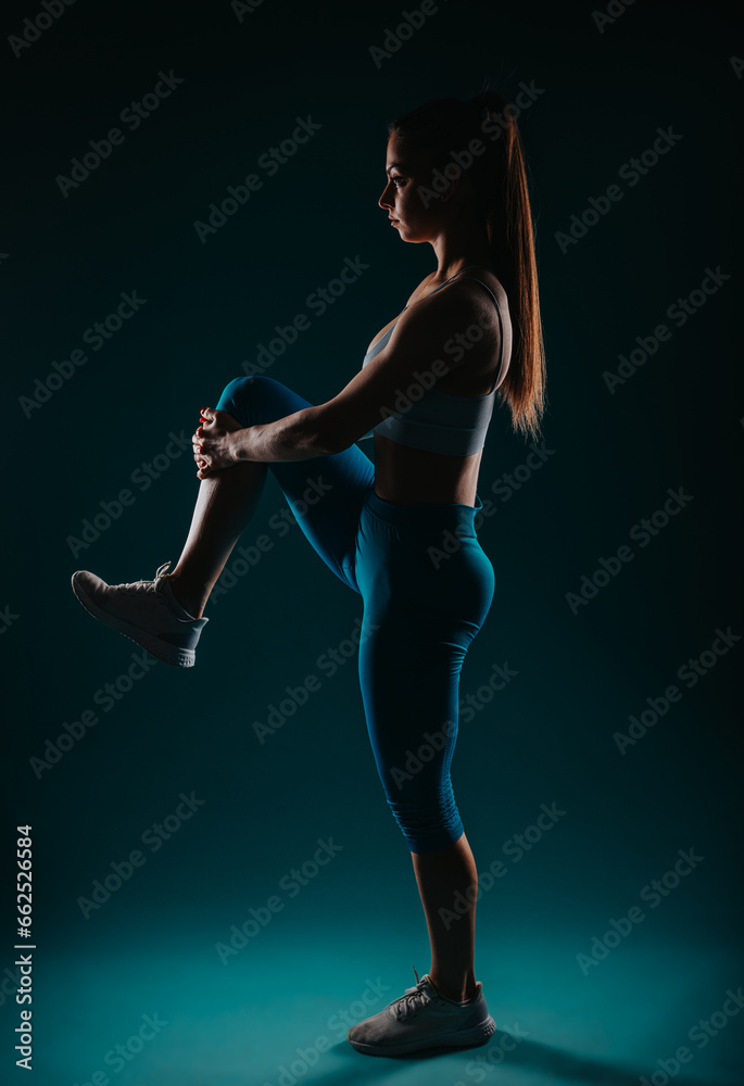 Fit Girl Exercising and Transforming Her Body in a Dark Studio Shot
