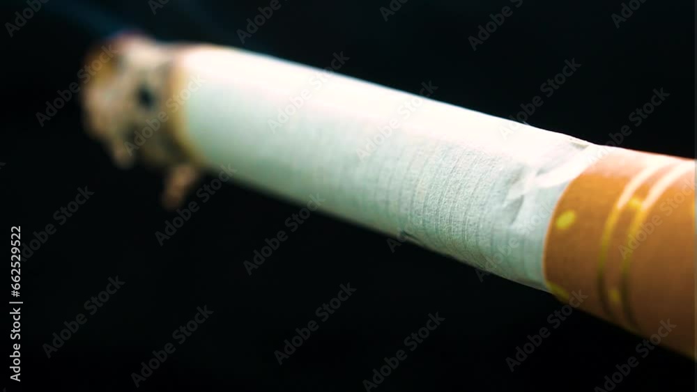 tailor made cigarette static on black backdrop burning from ne end