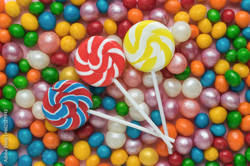 Three round lollipops on a stick on a background of colorful candies. The concept of sweets.