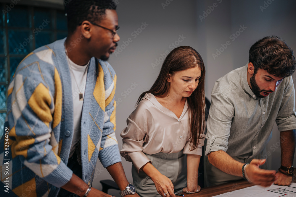 Obraz premium Successful Multiracial Business Team Collaborating on Architectural Blueprints in Office Meeting