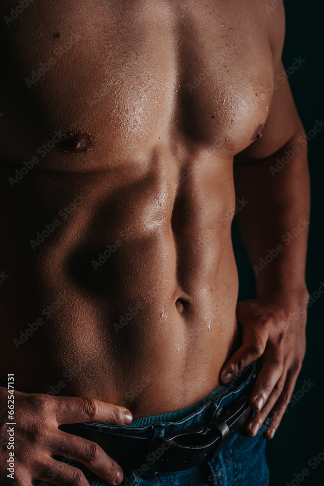 Fit male bodybuilder with fit six pack abs posing with hands on spine. Sweaty male chest, torso. Fit male bodybuilder with fit six pack abs posing with hands on spine. Sweaty male chest, torso.