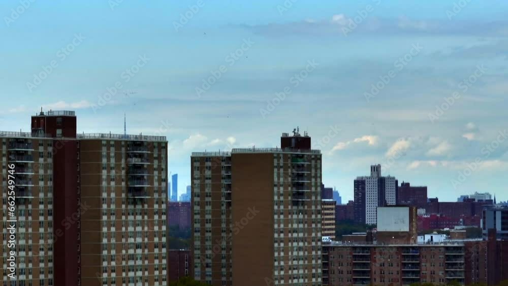 An aerial view of East New York in Brooklyn on a beautiful day. The camera slowly boom up in front of apartment buildings and the telephoto lens reveals the New York City skyline in the background. An aerial view of East New York in Brooklyn on a beautiful day. The camera slowly boom up in front of apartment buildings and the telephoto lens reveals the New York City skyline in the background.