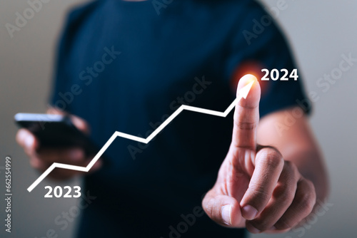 Businessman pointing at virtual graph target goals year 2023 to 2024. Resolution statistics graph year 2024. Chart plan management economic finance marketing goal future.