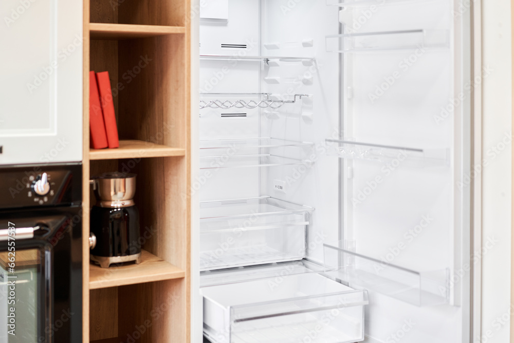 Refrigerator. Open door of an empty fridge. Household appliances in the store. Electrical equipment and household goods. Kitchen appliances in the mall.