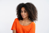 Friendly authentic woman with curly hair wearing orange t shirt with curly hair looking at camera