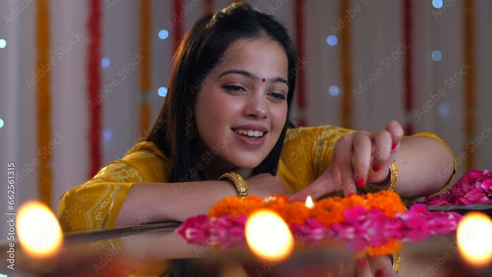 Beautiful Indian female placing a welllit oil lamp in the center of a