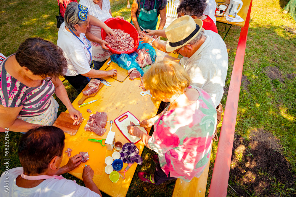 Fototapeta premium Overhead view on elderly man and several women are cutting are cutting meat