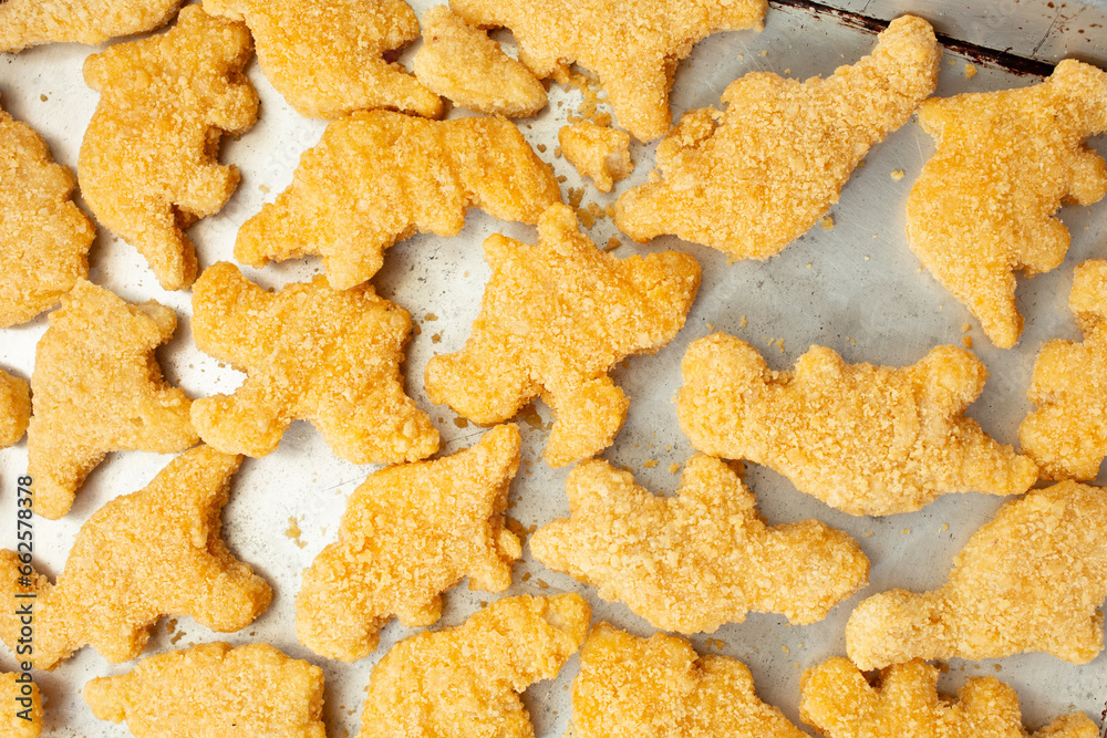 A top down view of a baking tray of dinosaur chicken nuggets. A top down view of a baking tray of dinosaur chicken nuggets.