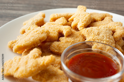 Fototapeta Naklejka Na Ścianę i Meble -  A closeup view of a plate of dinosaur chicken nuggets.