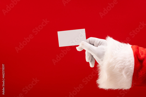 Santa claus holding white card with copy space on red background