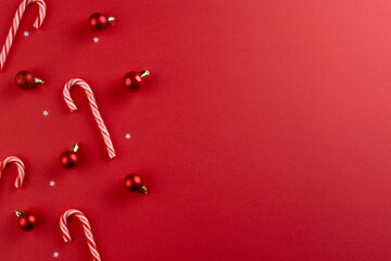 Christmas baubles decorations and candy canes with copy space on red background