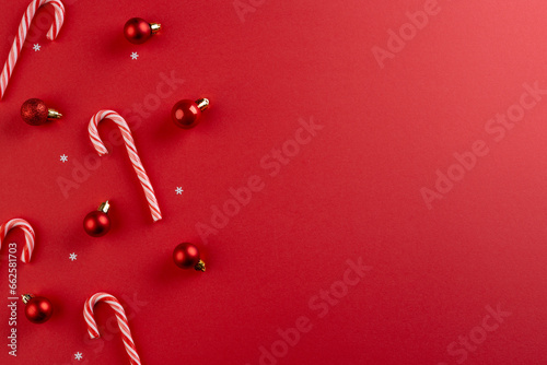 Christmas baubles decorations and candy canes with copy space on red background