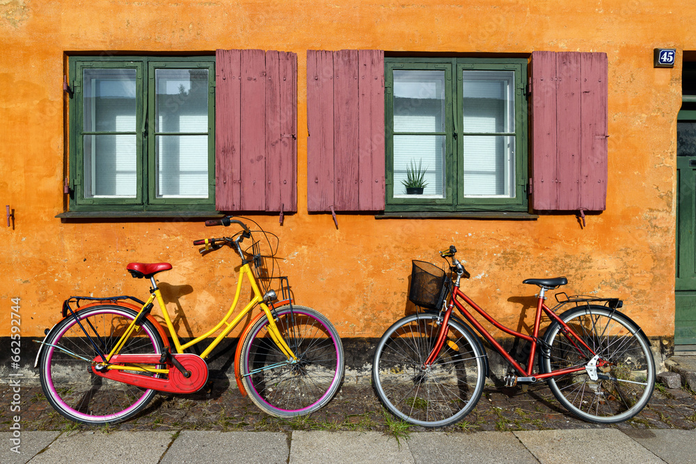 Obraz na płótnie Bicycles in front of an orange house facace in Nyboder (historic row house district of former Naval barracks in Copenhagen, Denmark). w salonie