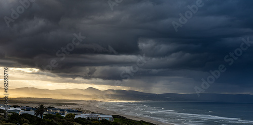 rain clouds over mountain and ocean with sun rays shining through.