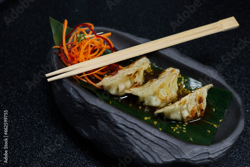 asiatic dumpling food, chicken and prawns stuffed gyoza with soy sauce in a black background.