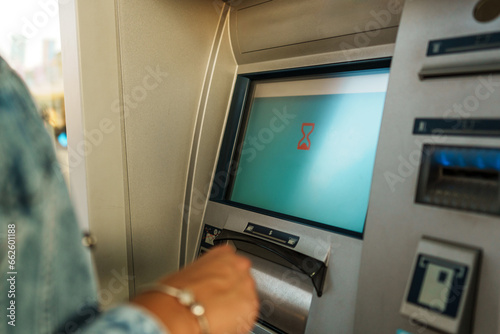 In a tightly framed shot, the woman's hands are shown while she inserts her card into the ATM and enters her PIN for secure access to her account.