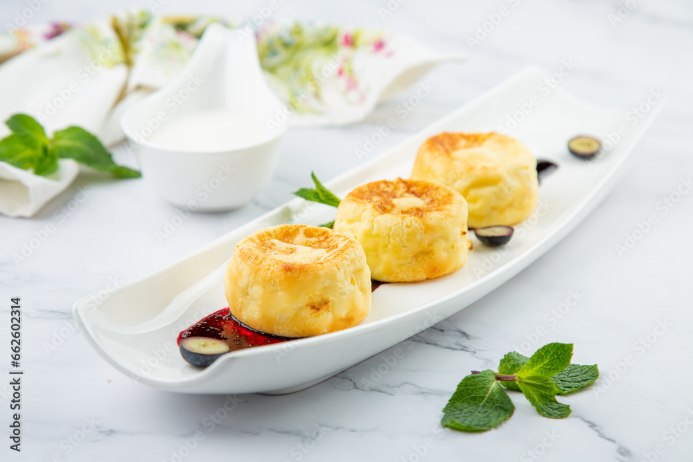 lush and tall cheesecakes with jam and mint on a white plate side view lush and tall cheesecakes with jam and mint on a white plate side view