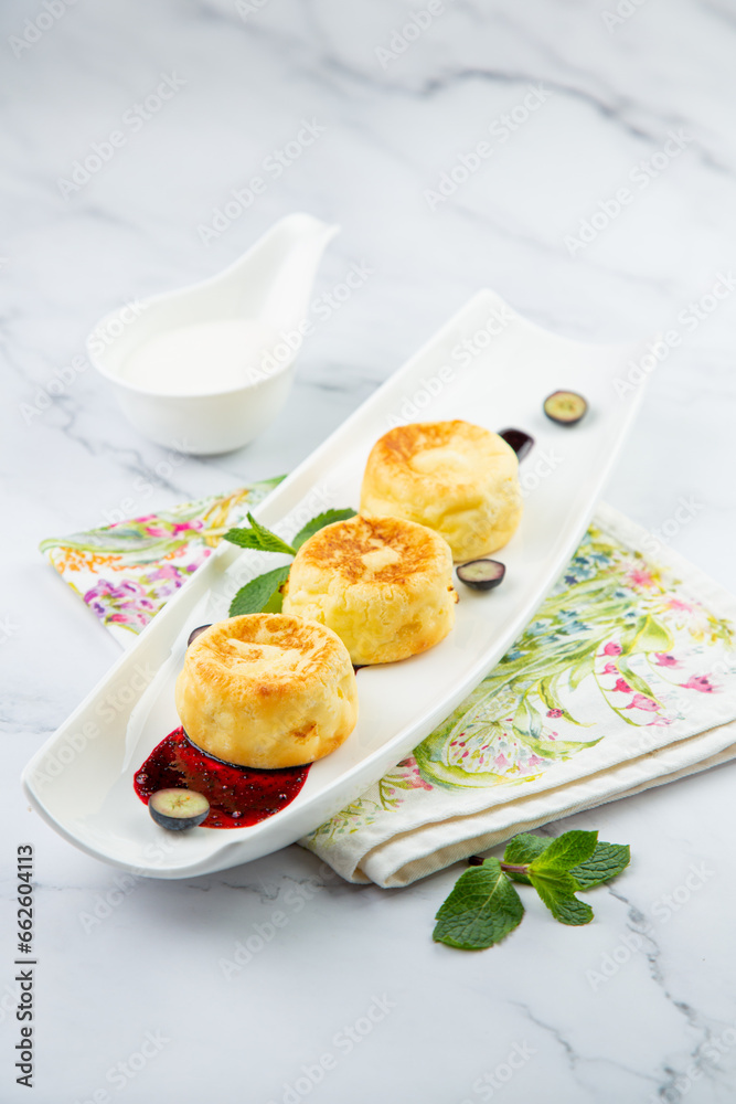lush and tall cheesecakes with jam and mint on a white plate side view lush and tall cheesecakes with jam and mint on a white plate side view