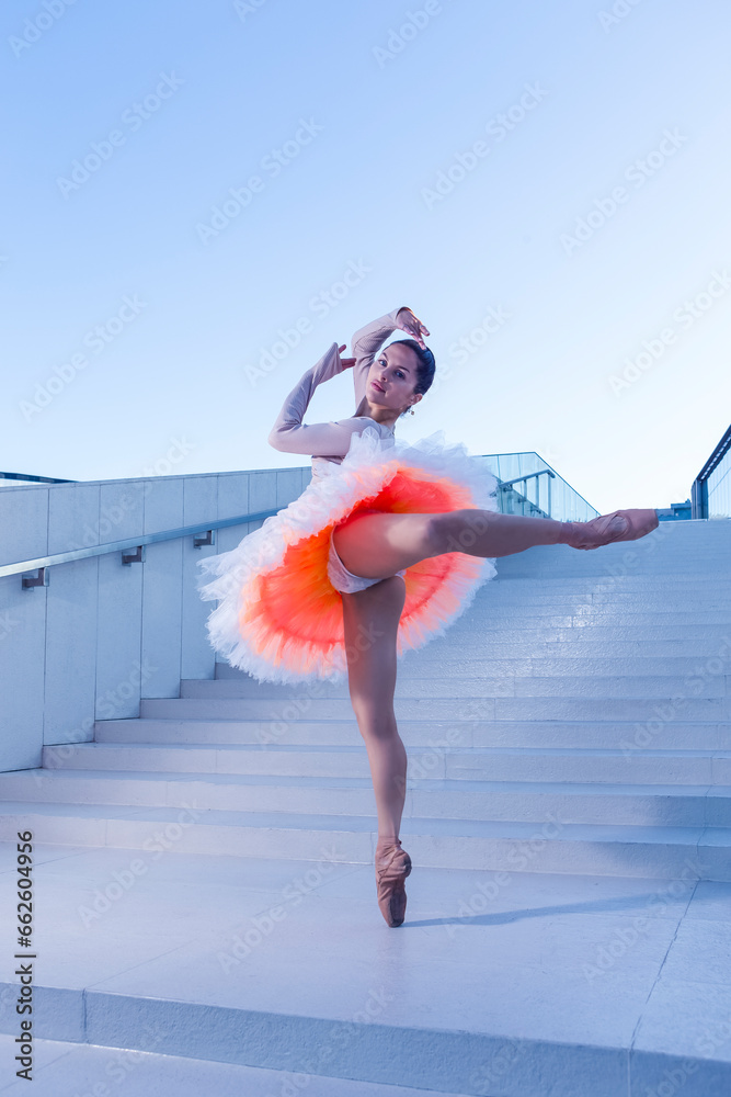 Fototapeta premium Graceful Winsome Sexy Slim Professional Caucasian Ballet Dancer in Rose Pink Tutu Dress Whie Posing In Dance Flying Pose Against Blue Stairs In Stretched Pose