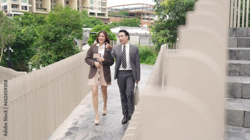 4K Confidence Asian businessman and businesswoman colleague holding briefcase and digital tablet walking city street at office district. Business people company employee go to work in the morning. 4K Confidence Asian businessman and businesswoman colleague holding briefcase and digital tablet walking city street at office district. Business people company employee go to work in the morning.