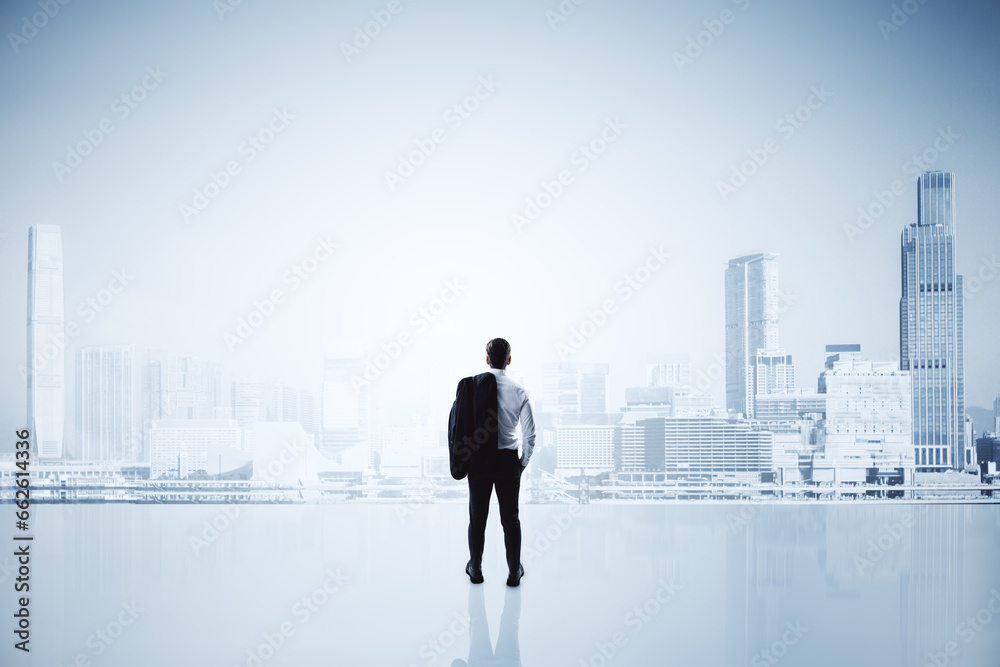Back view of young man standing on white bright city background with mock up place. Future, success and career concept.