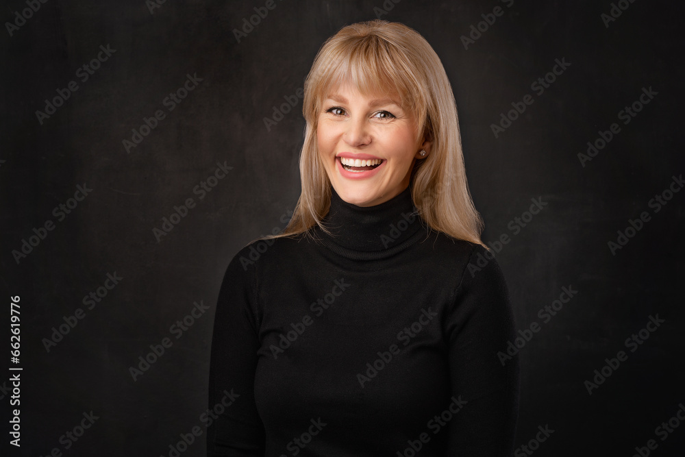 Confident blond haired woman wearing black turtleneck sweater against dark background Confident blond haired woman wearing black turtleneck sweater against dark background