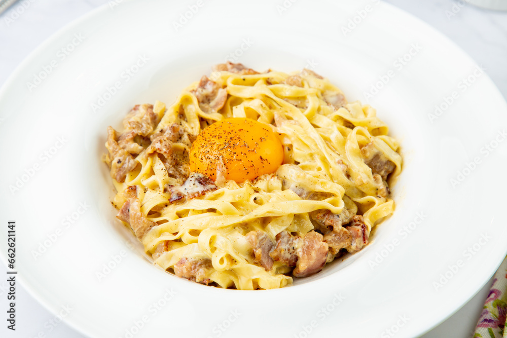 pasta in cream sauce with egg and black pepper on top side view