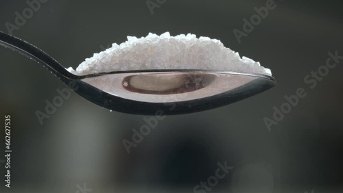 Spoon of white sugar. Close up slow motion blurred background. Sugar quietly infiltrates our diets. Increased risk for chronic diseases like diabetes and heart disease. Overuse of sugar in products