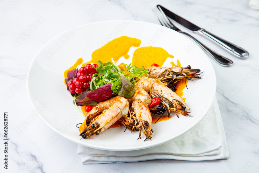 cooked shrimp with herbs and berries on a white plate, side view