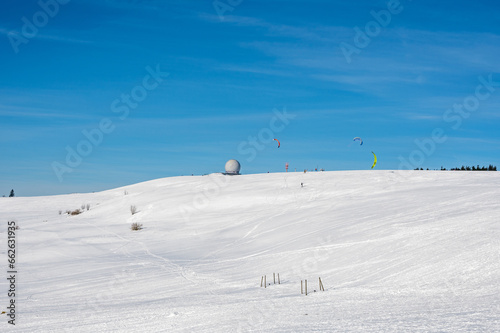 Kite surfing on the Wasserkuppe with Radome in the snow with a blue sky