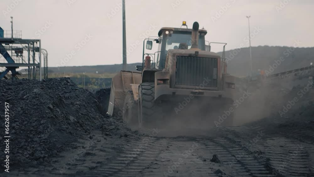 In the stark backdrop of the mine, a front end loader casts a formidable shadow as it drives away, symbolizing the unending pulse of industrial work and the raw essence of resource extraction
