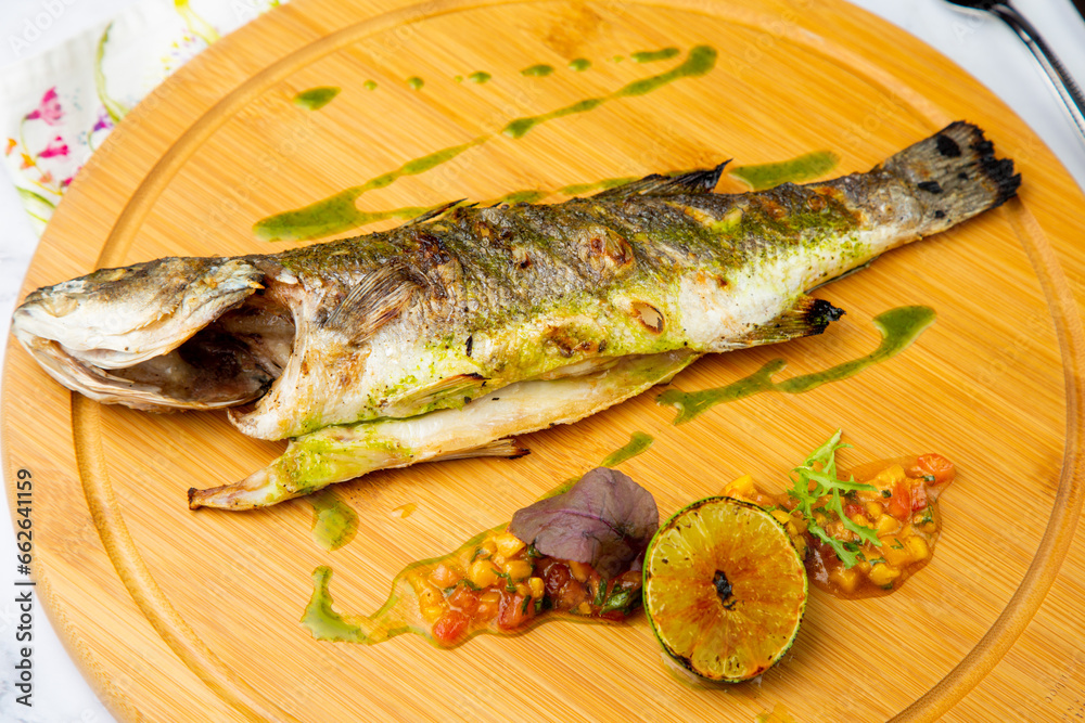 baked fish with spices and lemon on a wooden tray side view baked fish with spices and lemon on a wooden tray side view