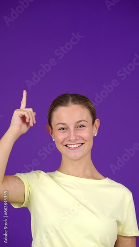 Teenager girl showing purple copy space. Young woman pointing up isolated on plain background