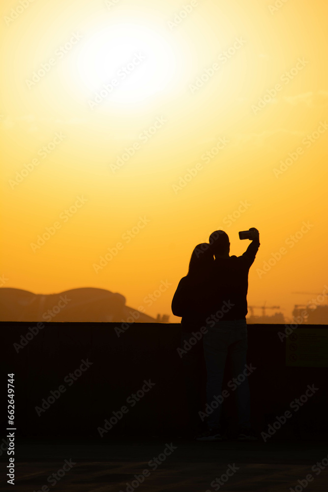 Sunset and lovers. Woman and man against the backdrop of sunset. Orange sky and sun