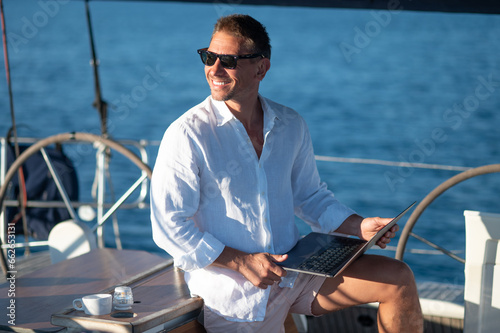 Smiling man traveling on a yacht and looking contented photo