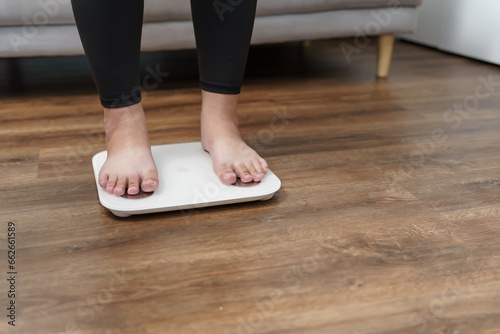 Fat diet and scale feet standing on electronic scales for weight control. Measurement instrument in kilogram for a diet control.