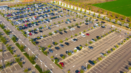 Aerial view of the Reggio Emilia AV Mediopadana station car park. There are many cars parked but also some empty spaces.
