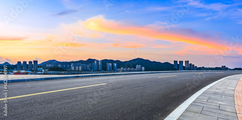 Asphalt road and residential buildings at sunset by the sea © ABCDstock