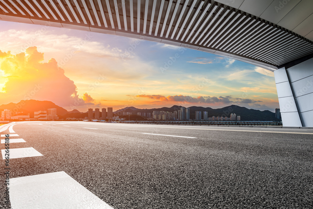 Naklejka premium Asphalt road and skyline with residential area buildings at sunset