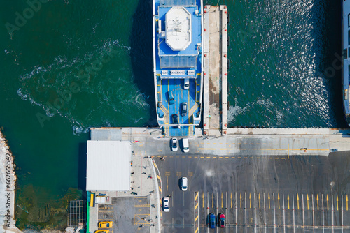 Cars drive off the deck of ferry boat onto the port in island. Top-down aerial drone shot © Leonid