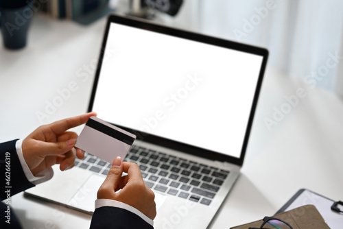 Close up female hands holding credit card and using laptop, doing online purchases or paying online