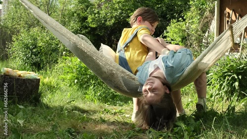 Brother and sister revel in joyful moments, swinging in a hammock, embodying harmonious living escaping the city's rush. Snapshot of blissful youth photo