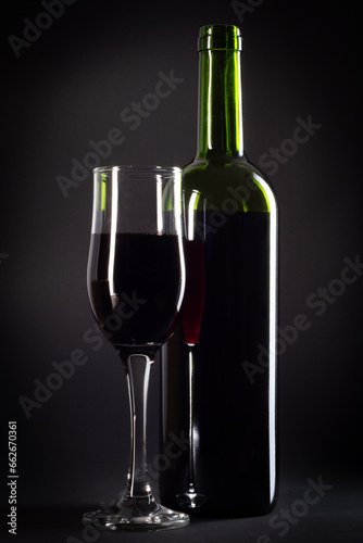 bottle and glass of red wine on a black background with copy space