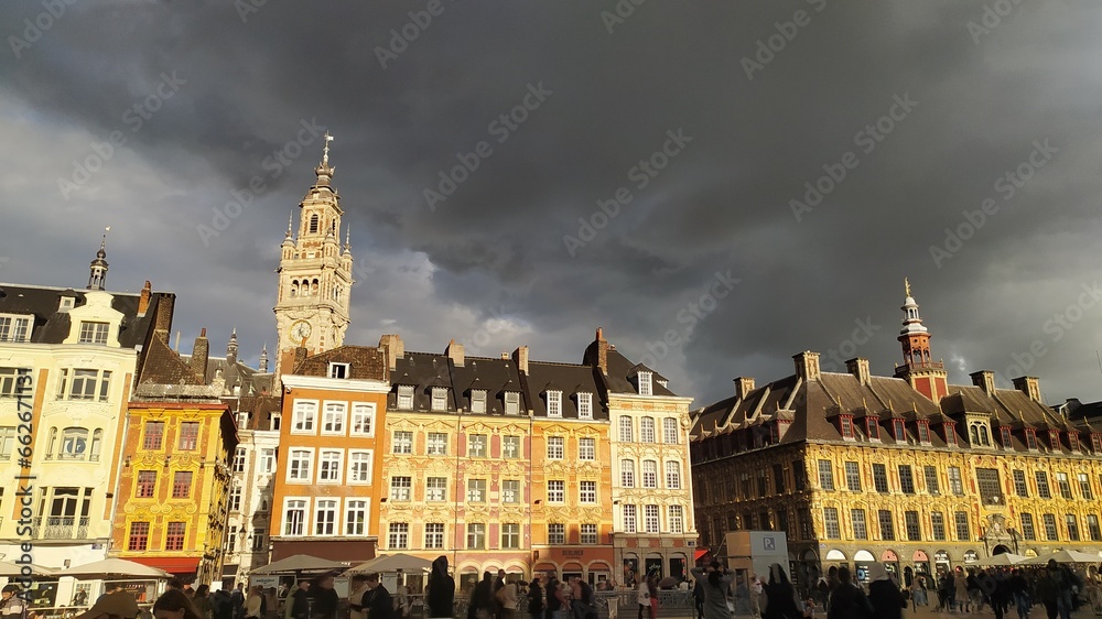 Magnifique vue des bâtiments baignés de soleil, Grande-Place de Lille, beffroi en arrière plan, ciel noir